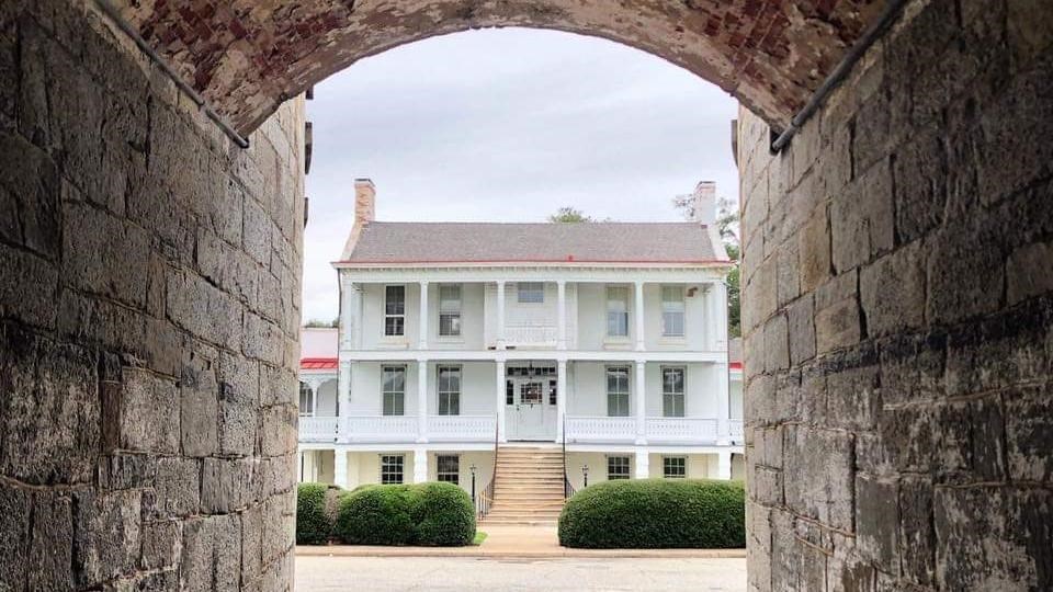 looking through the East Gate brick and stone sallyport at the three-story white brick building