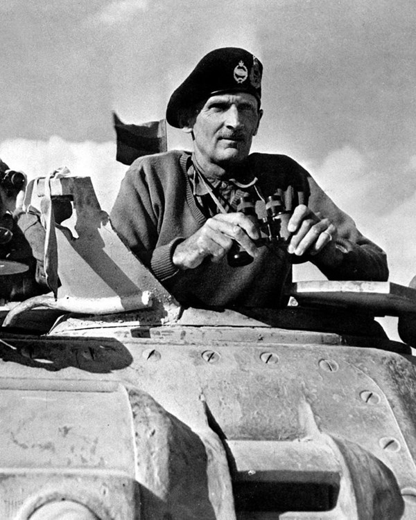A black and white image of a man standing in a tank holding binoculars