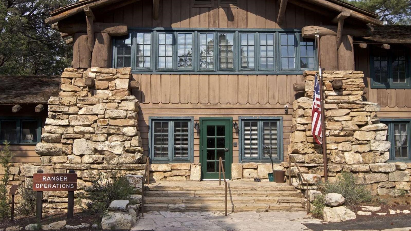 A two story wood and stone building with steps and an USA flag out front