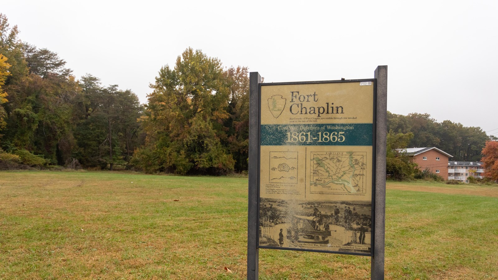 An informational panel in front of a grassy field. 