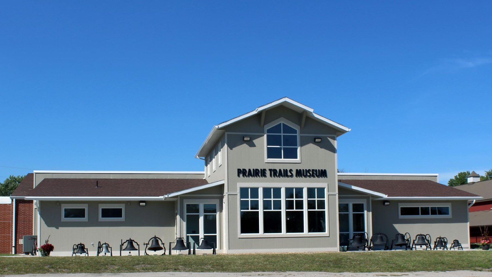 A paved path leads through a grassy lawn to a large red brick building.