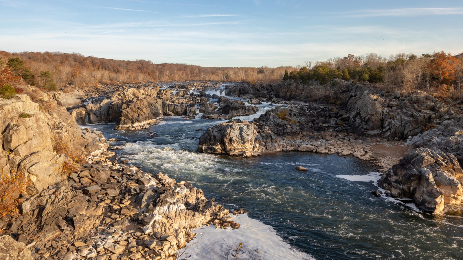 A large river rushing down a stream filled with large boulders. 