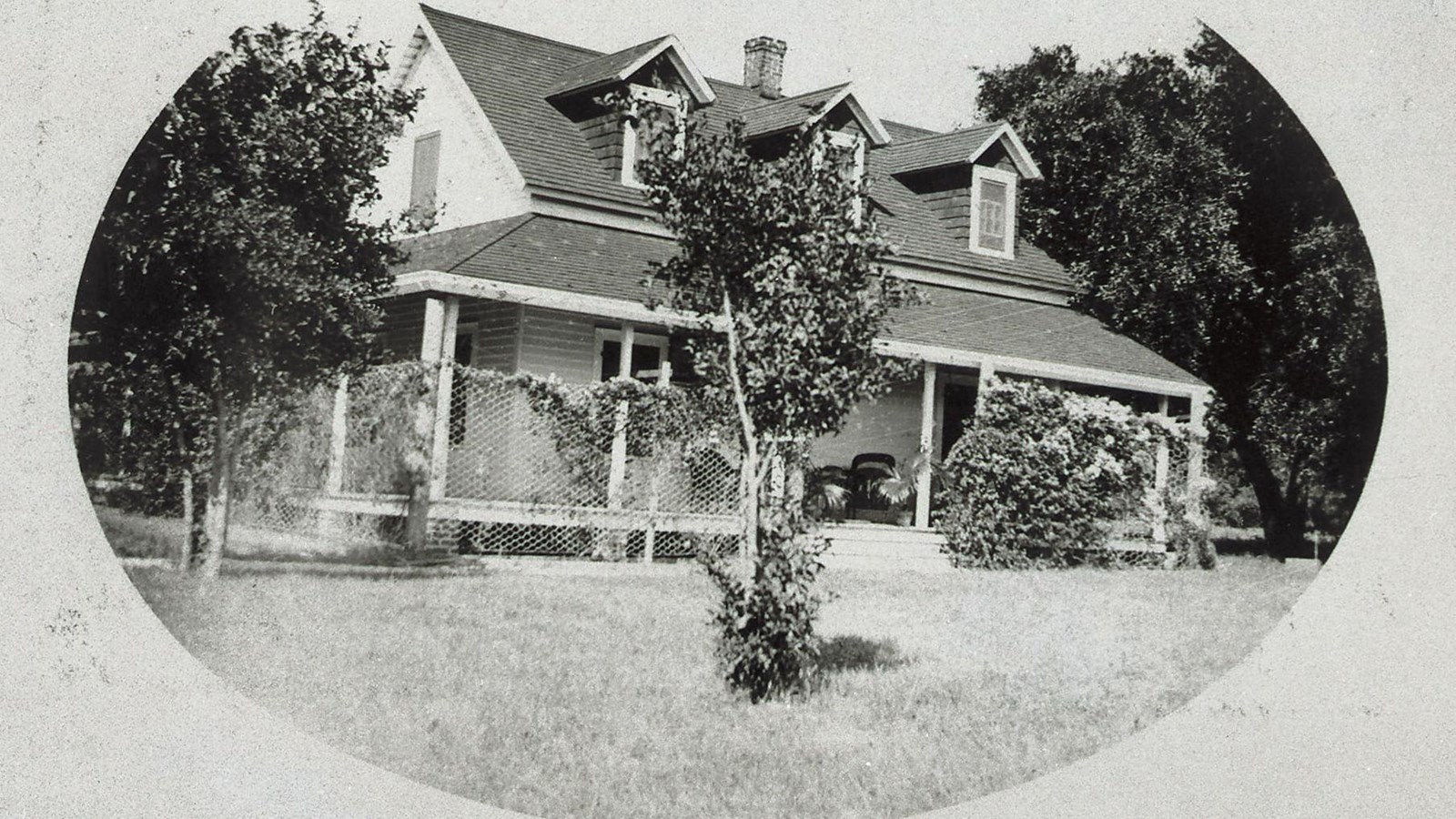Historic photo of the two-story Carnegie boat captain\'s house with front porch and greenery around. 