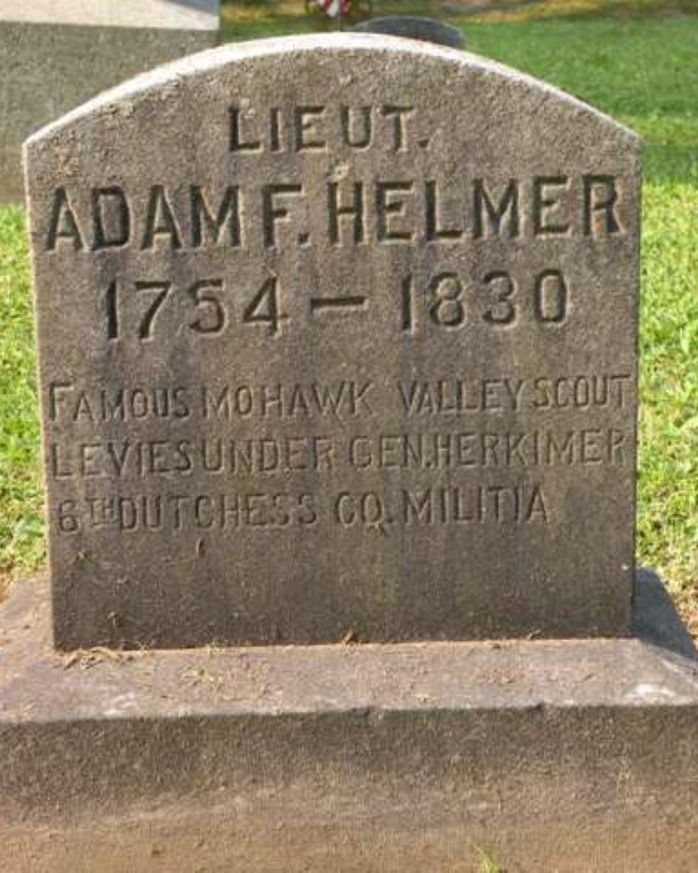 An old gravestone with the name "Adam Helmer" etched in block print at the top. 