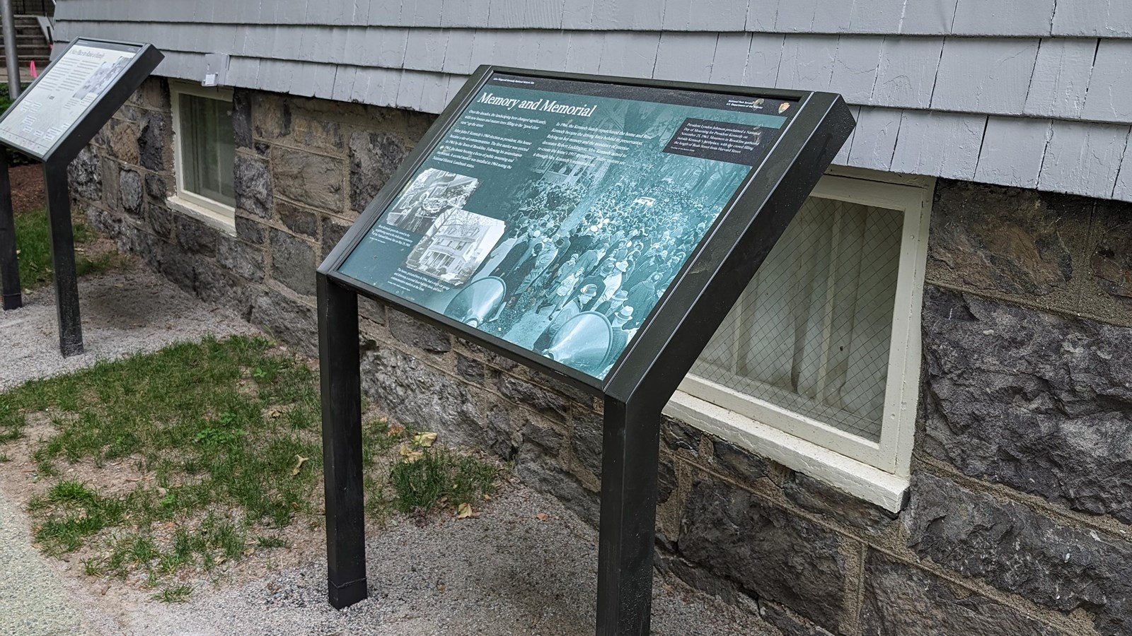 Wayside panel with green background next to side of gray house