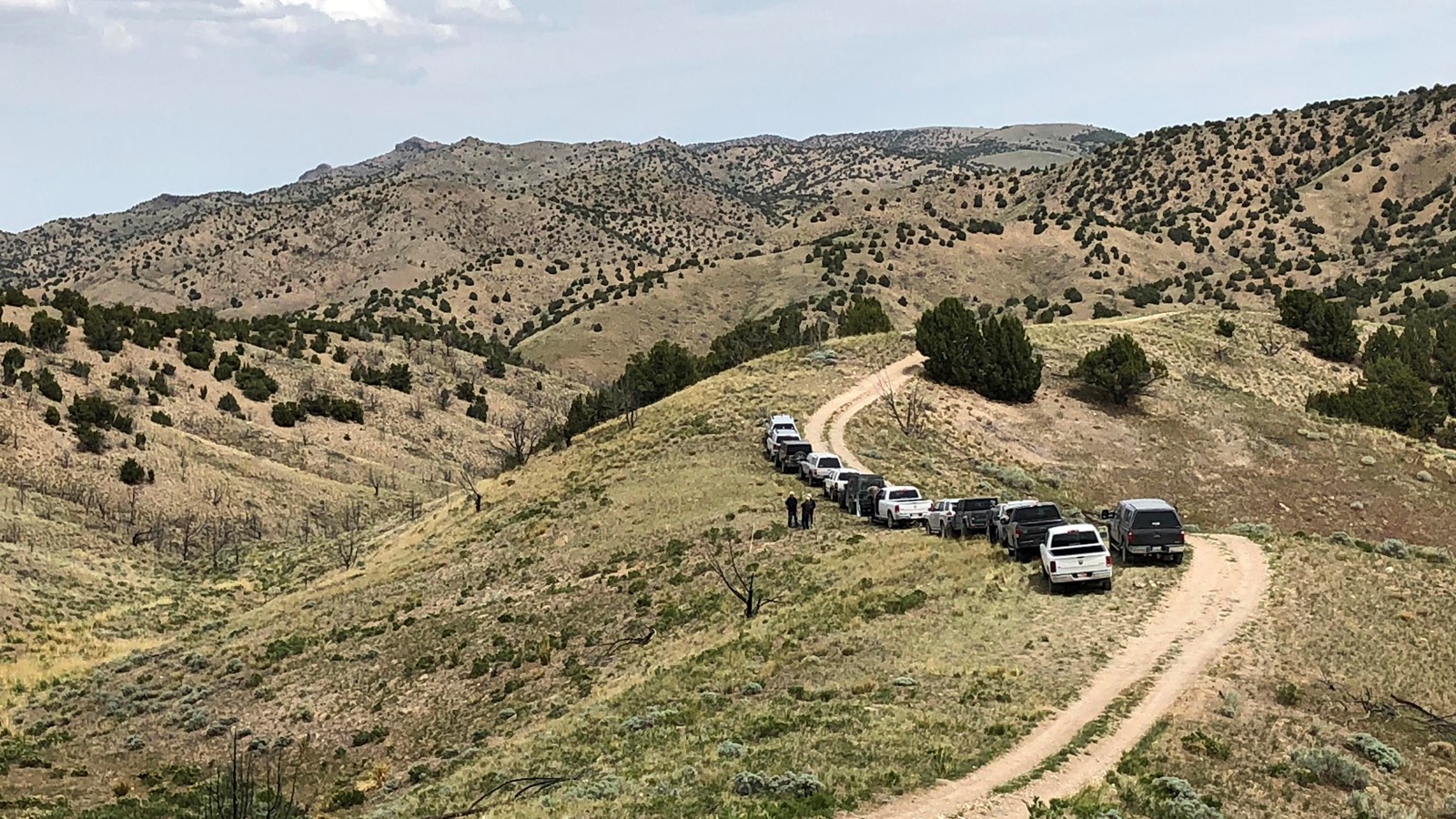 A two track dirt road along a ridge in a hill covered landscape.