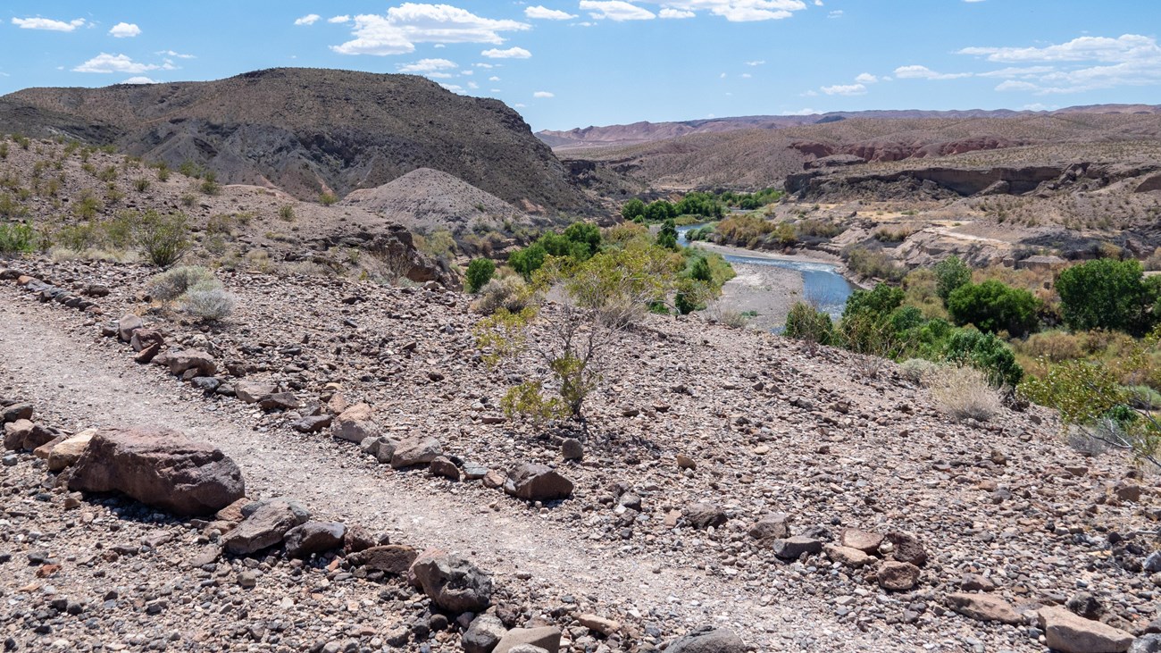 A trail winds above on a high vista overlooking a small stream.