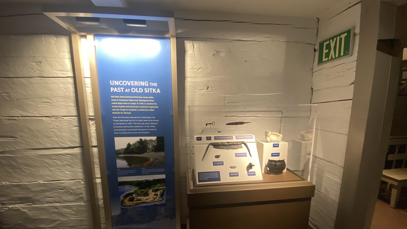 hallway painted white with red floors with an exhibit with objects found form an archeology dig