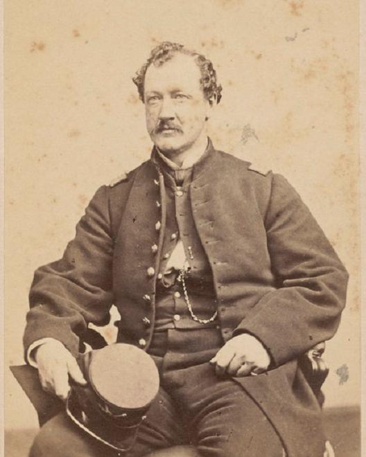White man with short curly hair and a mustache sitting in a Union army uniform