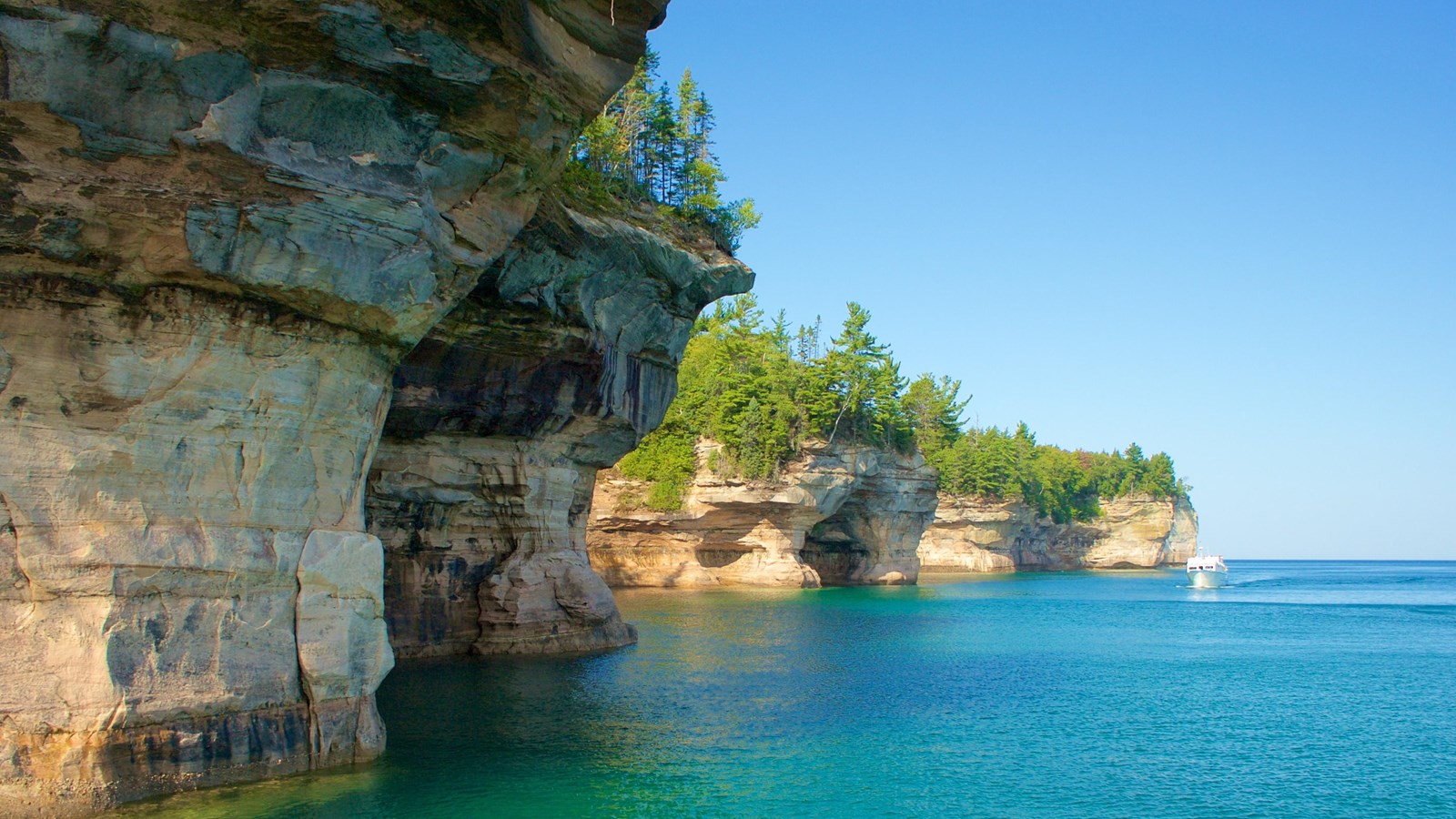 Sandstone cliffs rise out of Lake Superior. The rocks is mineral stained.