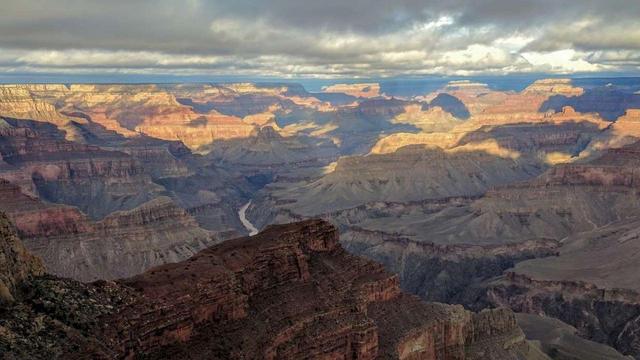 A colorful canyon landscape with clouds overhead