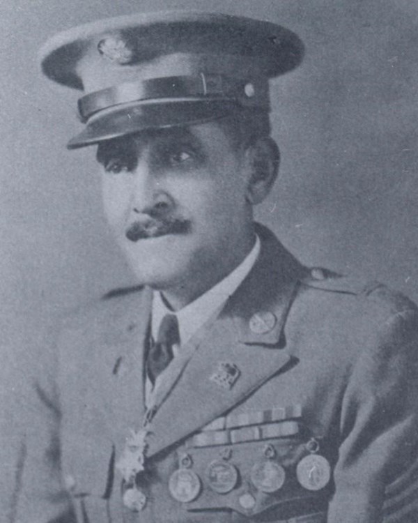 Black and white photo of African American man in military uniform. Several medals adorn his uniform