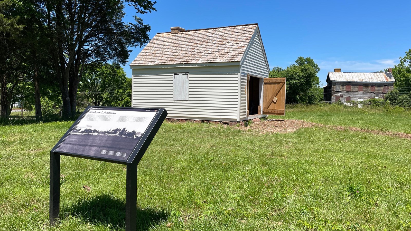 An information panel sits near a white building about the size of a one-car garage.