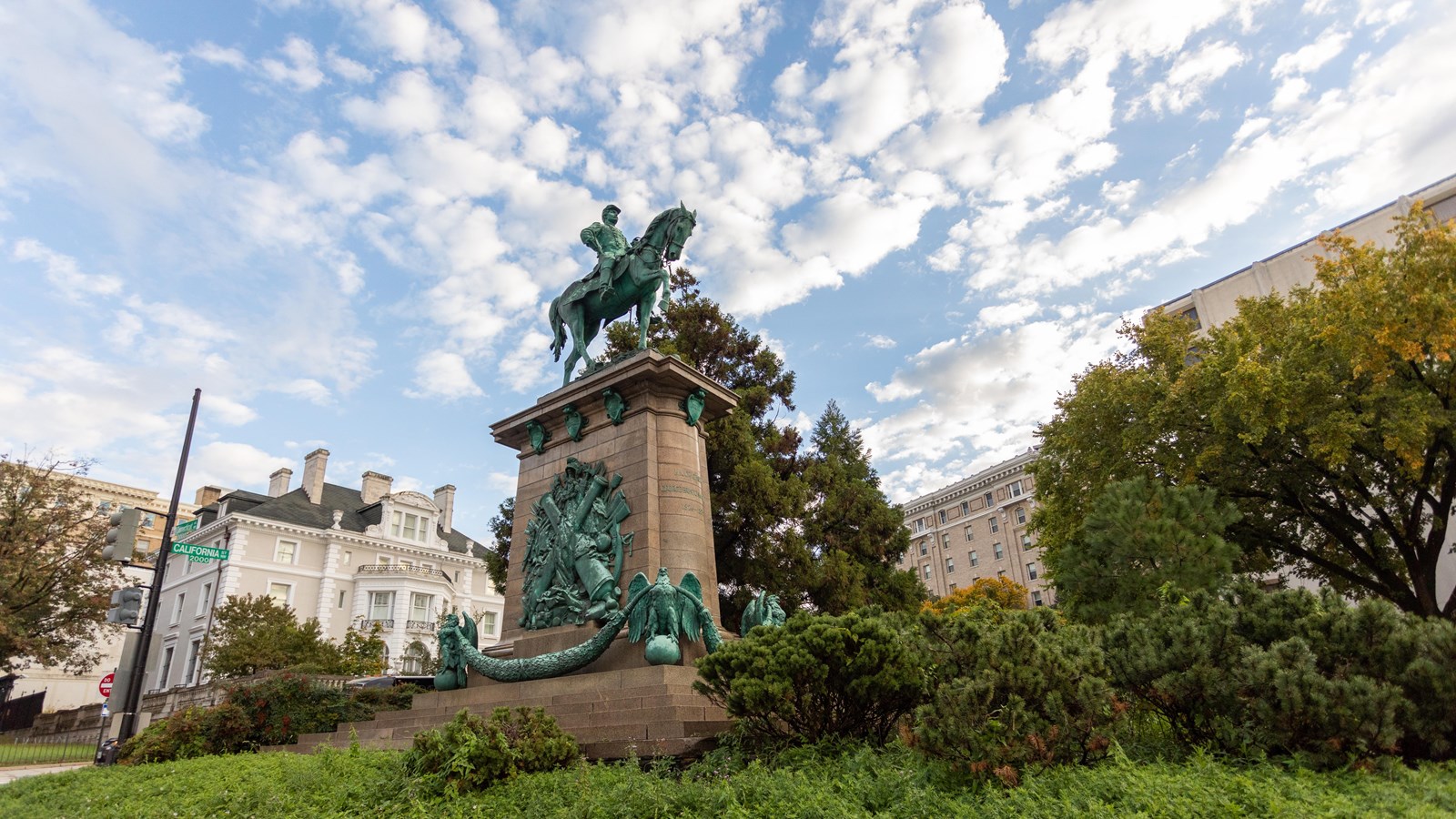 A large monument of a man on a horse in front of buildings. 