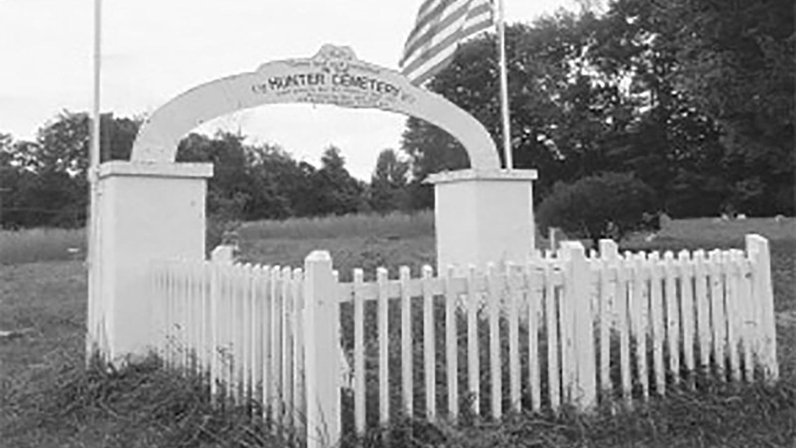 black and white photo of cemetery with gate and fence