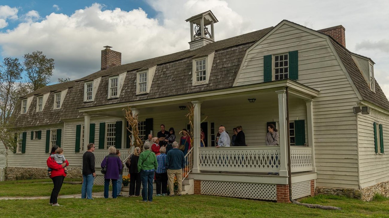 A group of people gather on the front steps of the lower farm house.