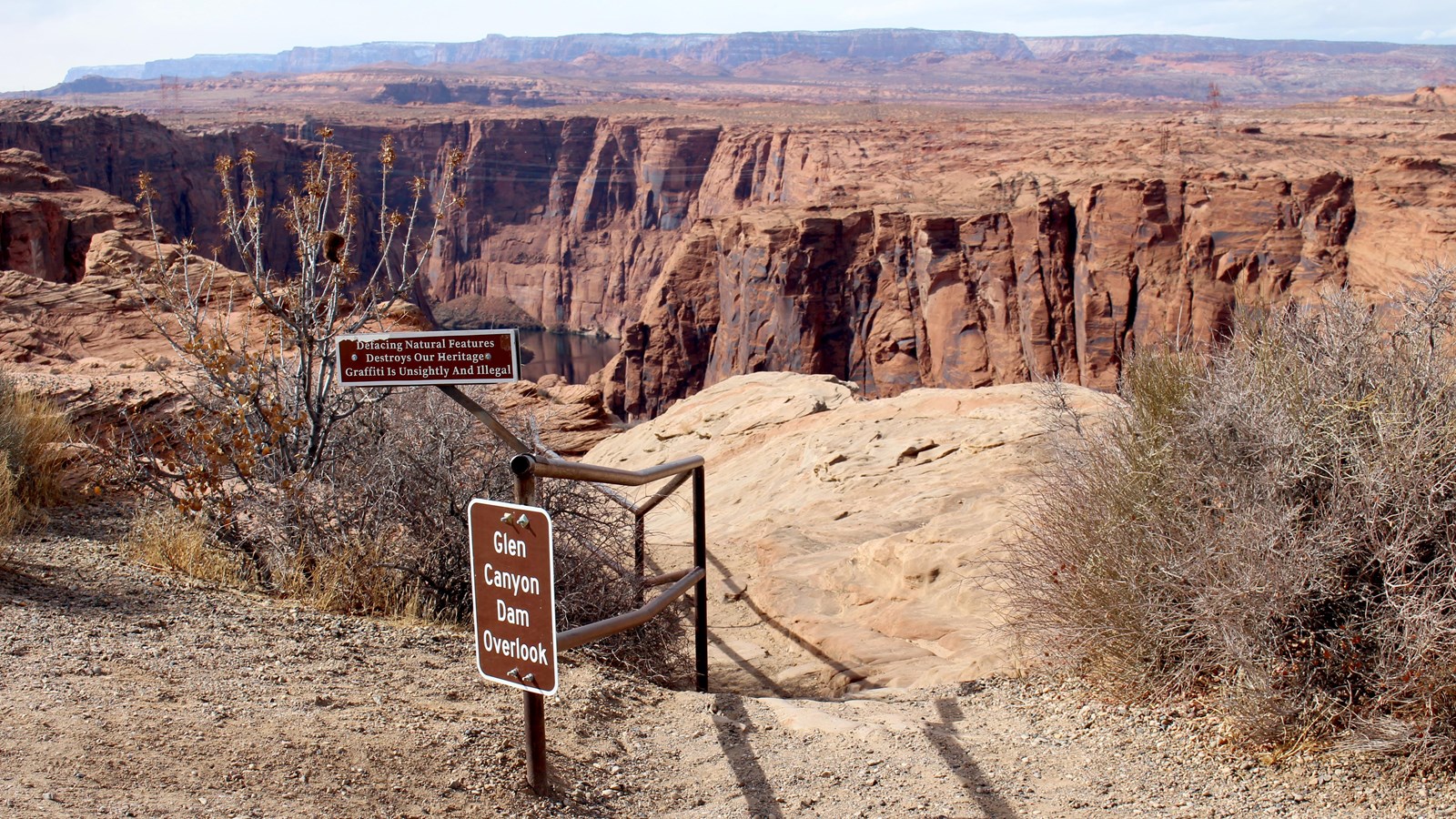 steps cut into sandstone lead down, metal rail and sign, 