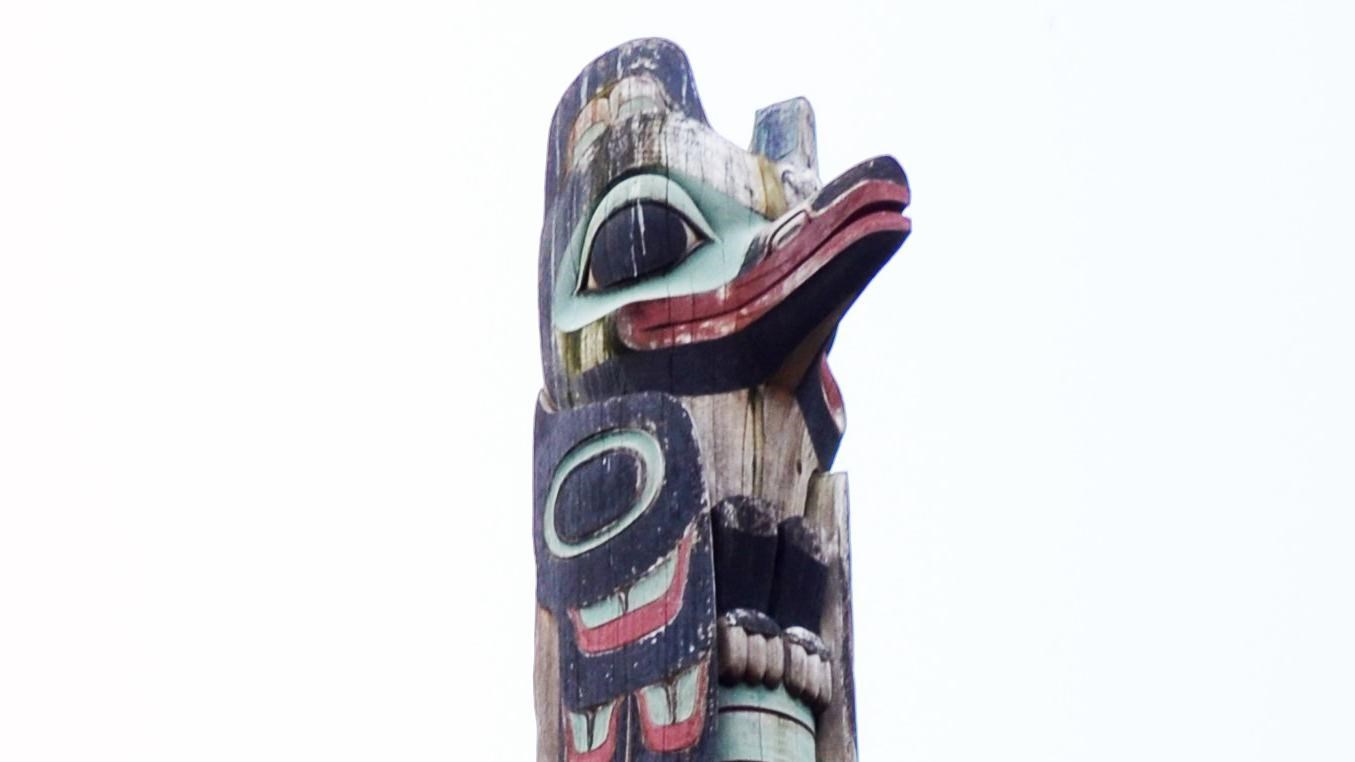 Top figure of a totem pole with sky in the background