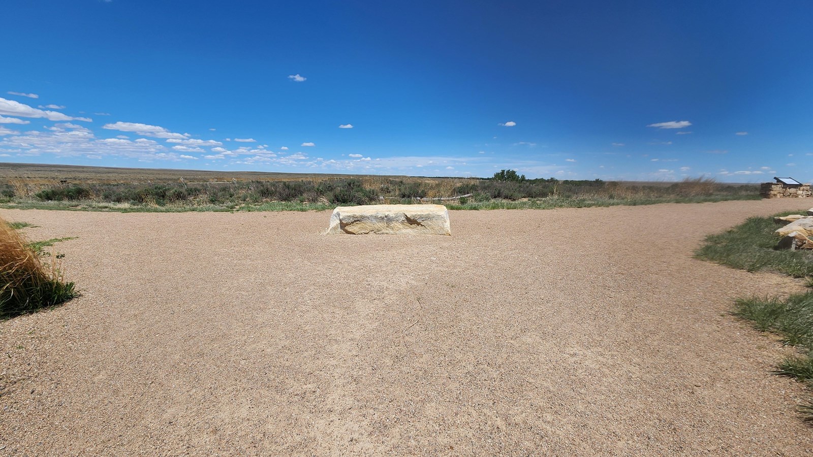 A boulder sits in the wide junction between three gravel pathways