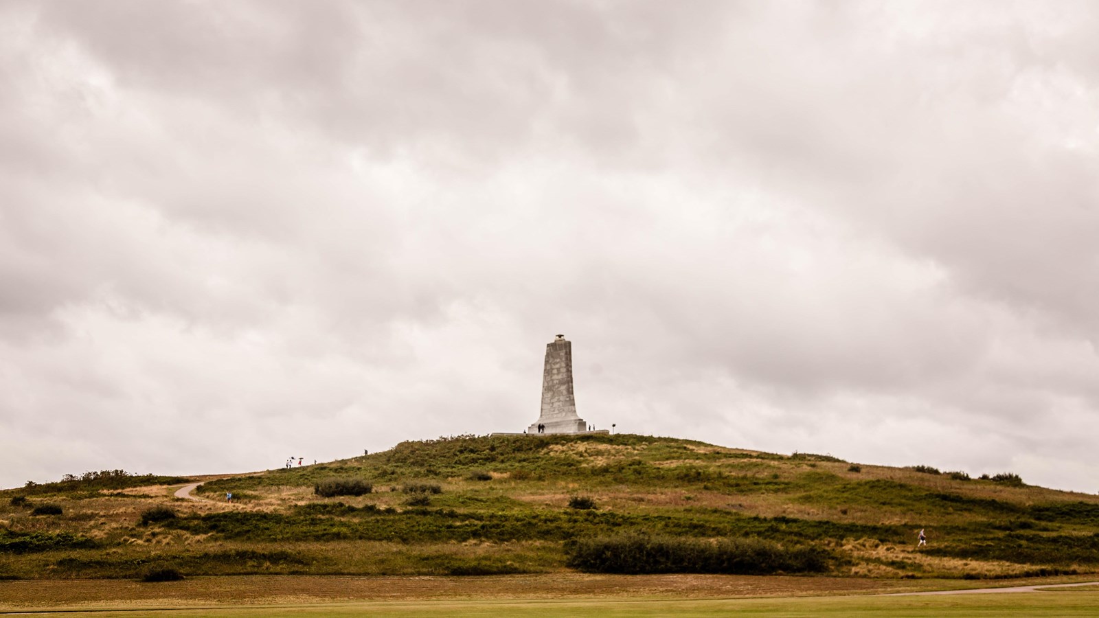 a monument at the top of a hill surrounded by a road