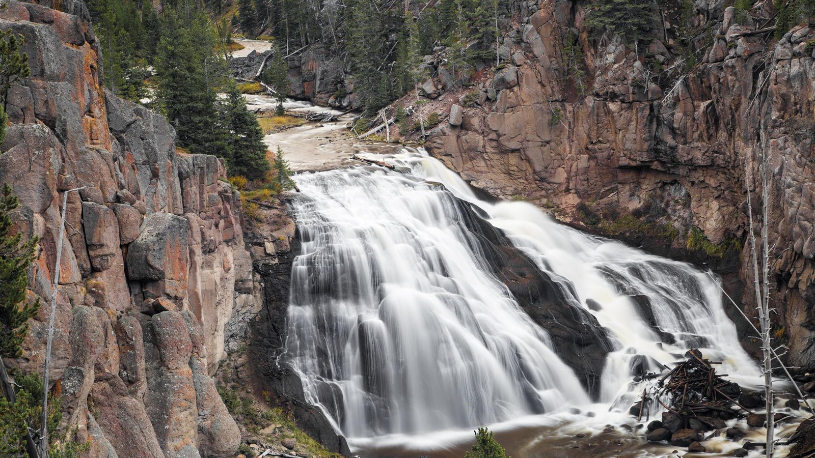 A river cascades 80 ft down over rocks in a canyon.