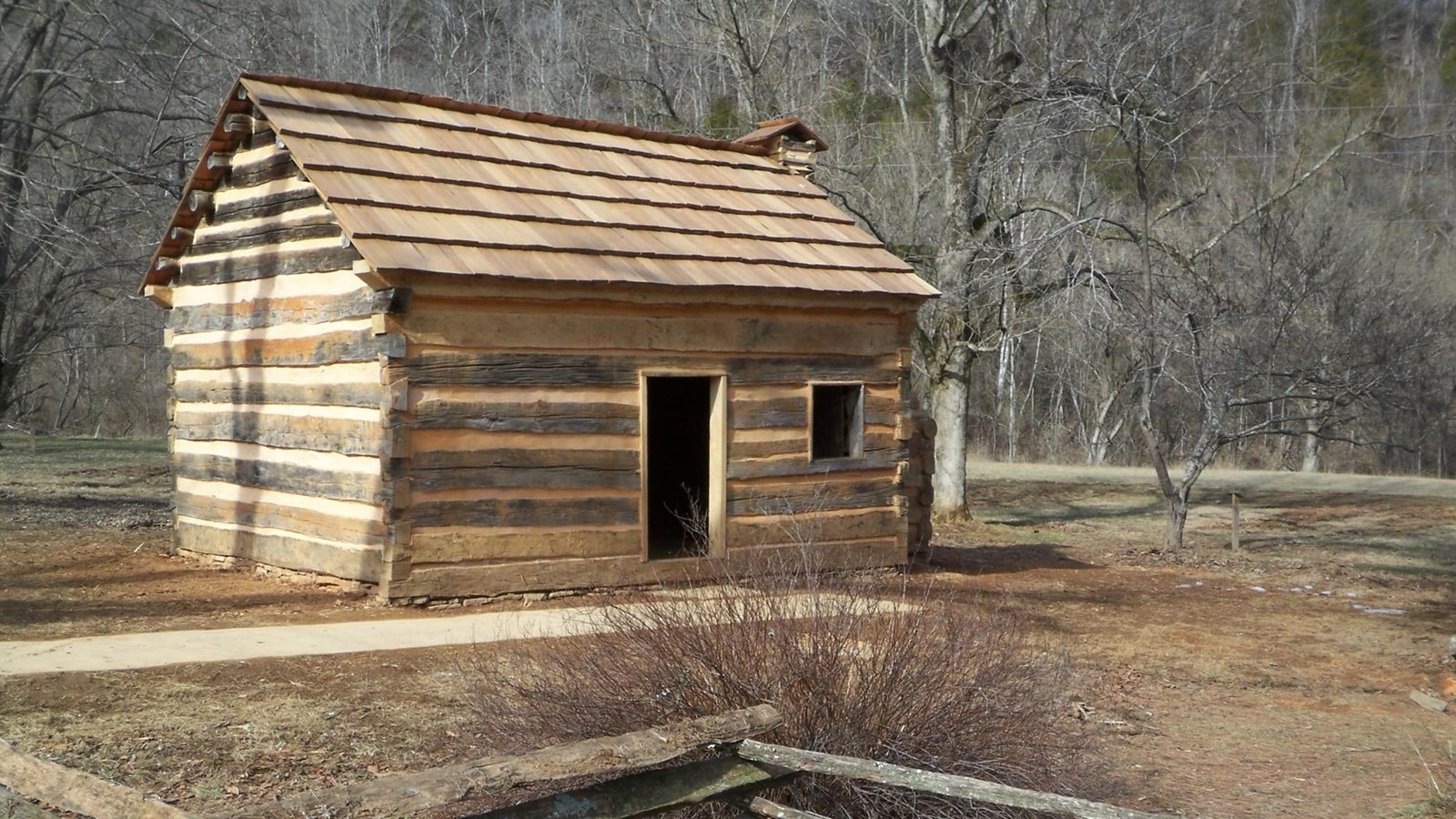 Small wooden cabin, surrounded by fields.