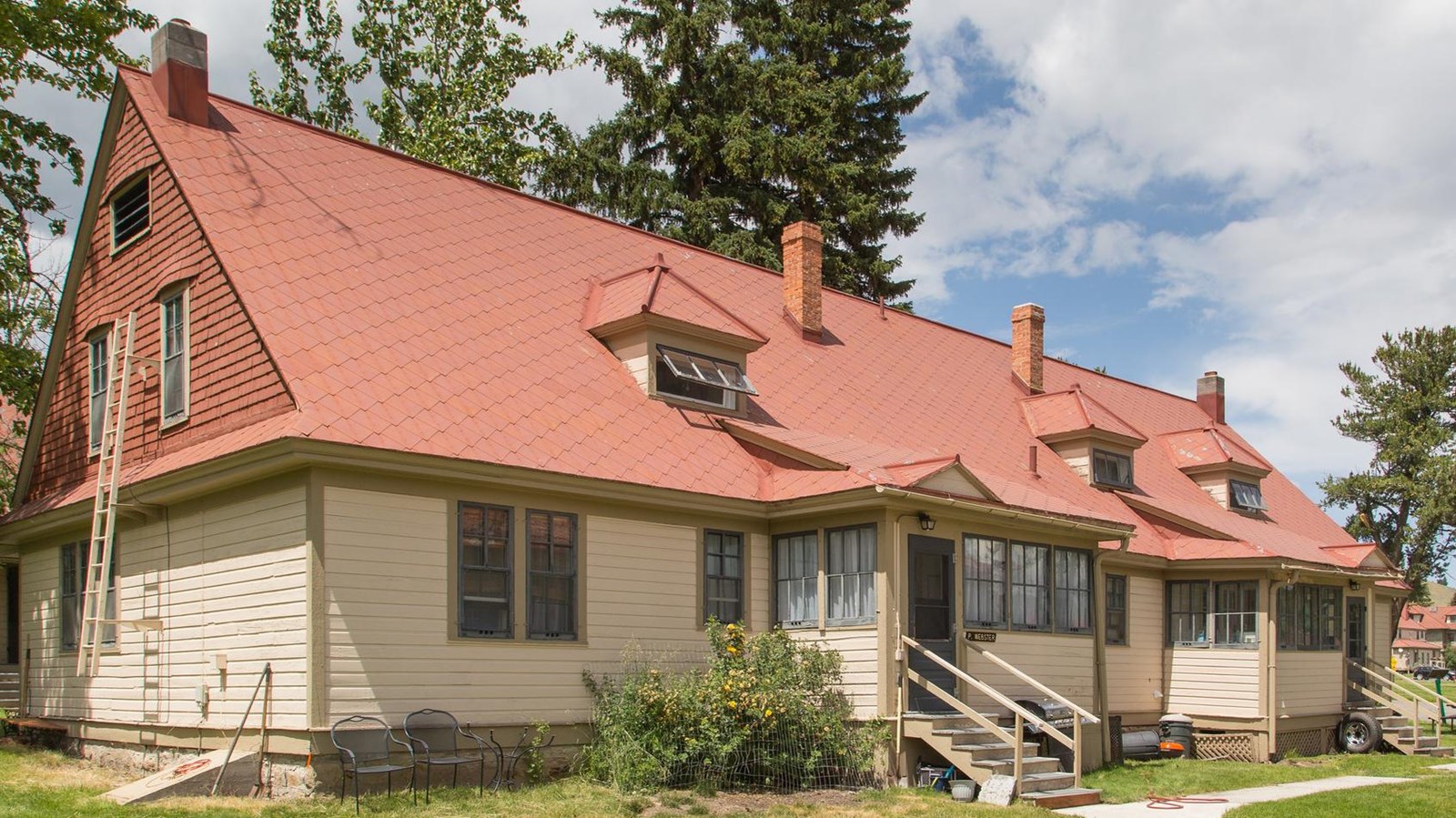 A historic building with pale, yellow siding and a red shingled roof.