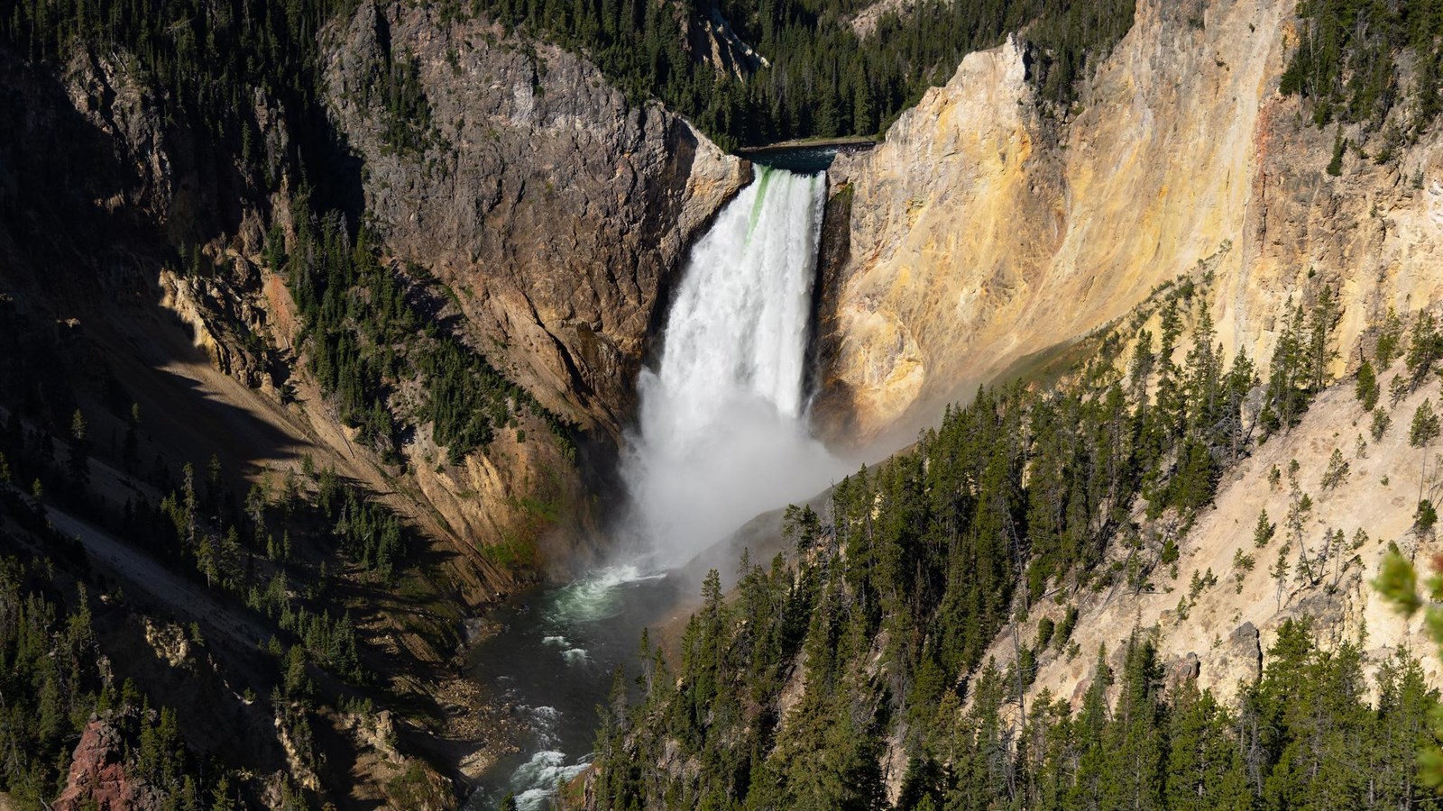 A river plunges 300 ft into a canyon with gray and yellow rock walls.