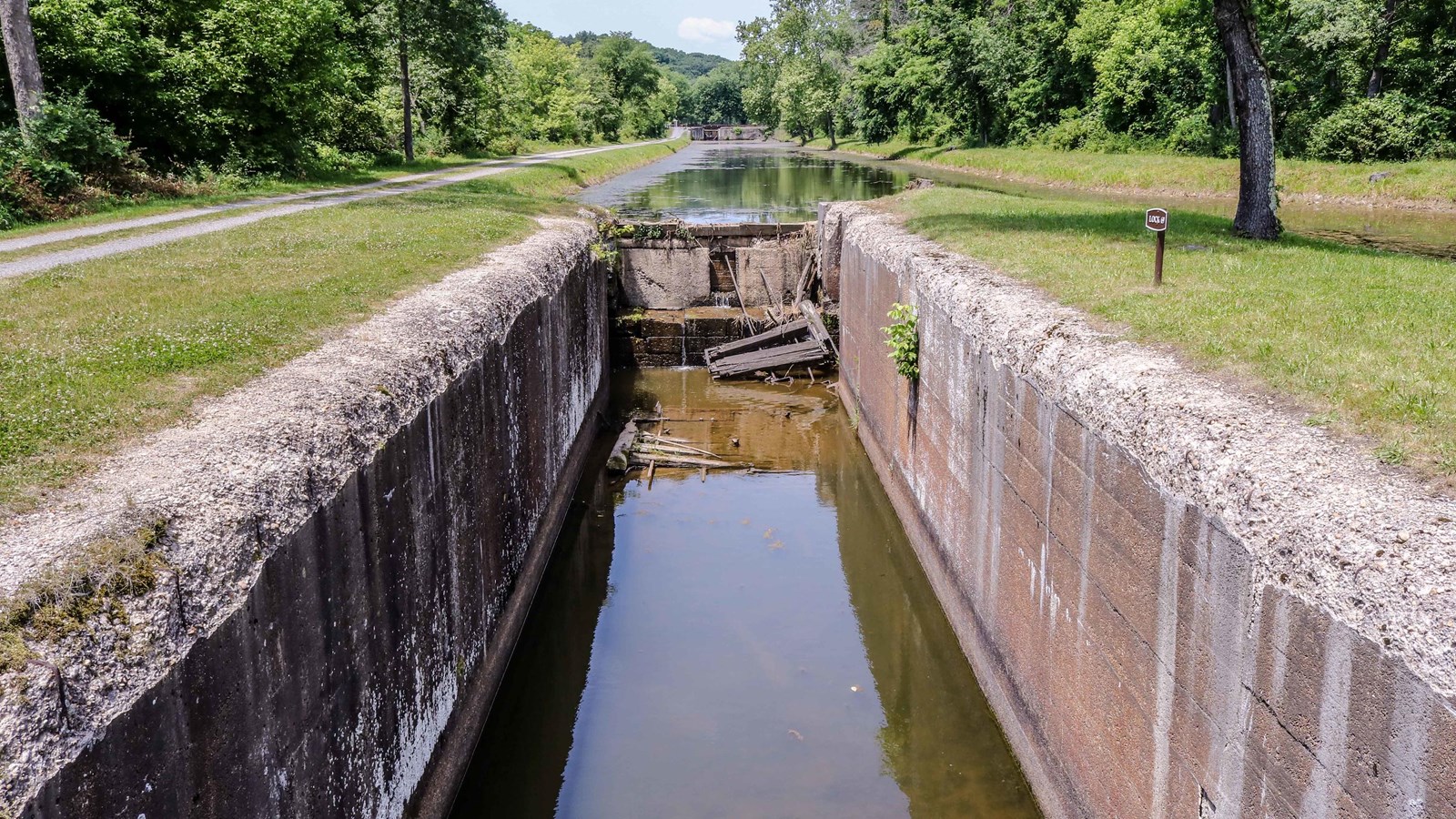 Looking down a water filled lock with two parallel stone walls on the right and left.