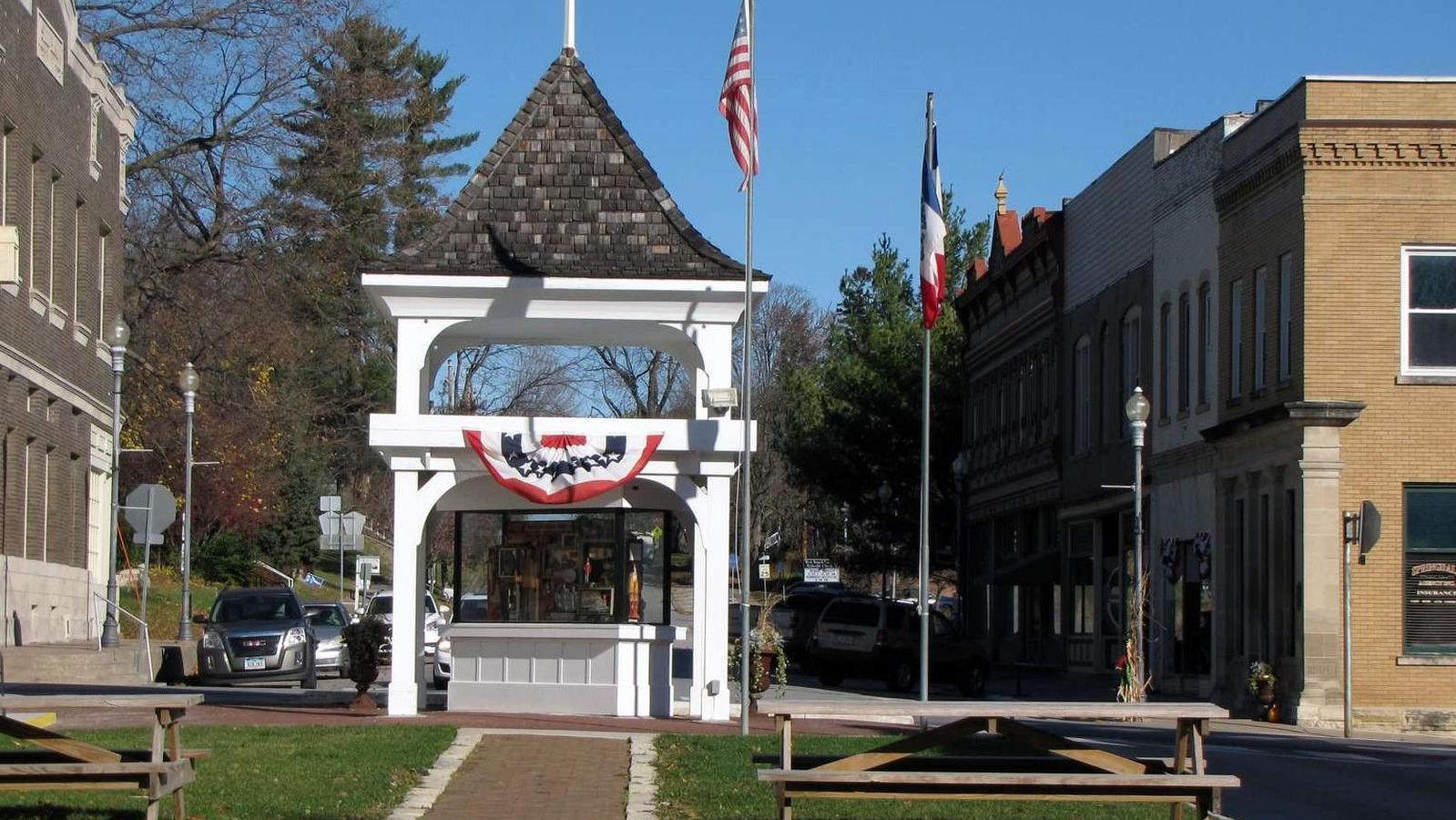 A white gazebo on a historic downtown street showcases local history with a art display.