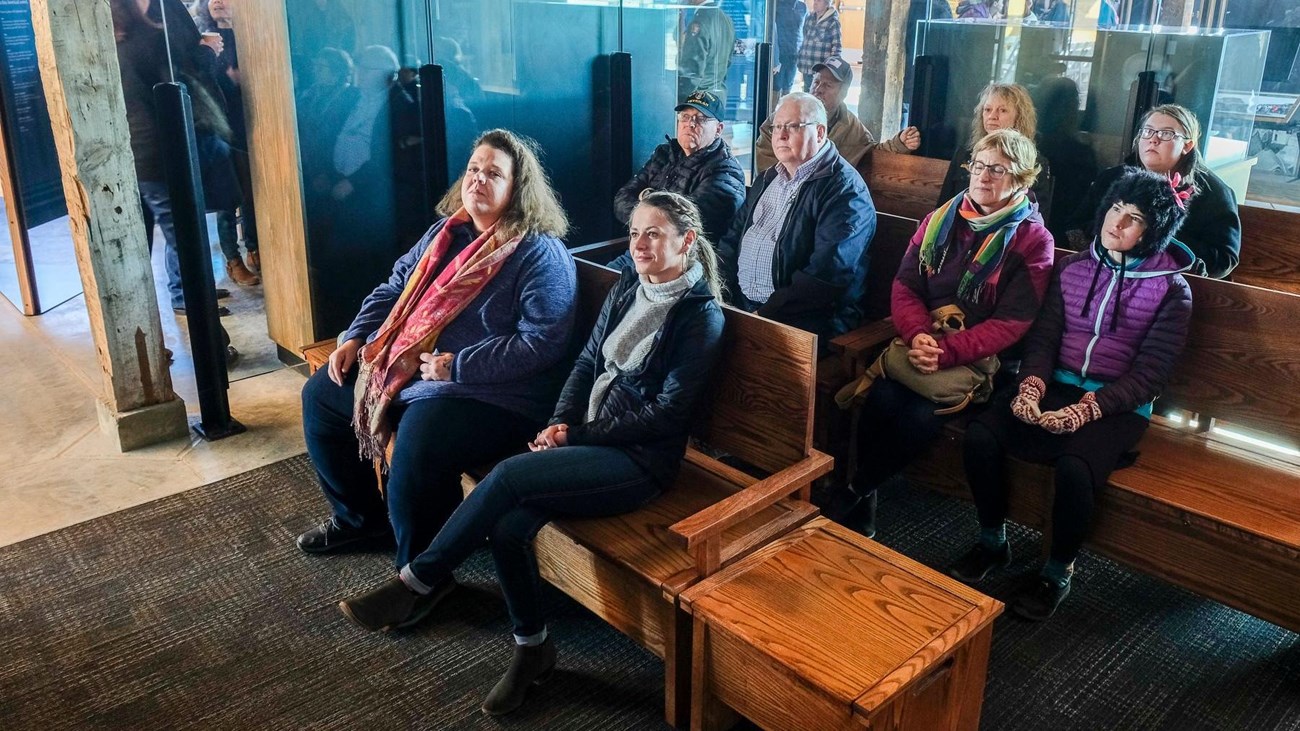 Visitors sit in a small theater seating area inside the Minidoka Visitor Center.