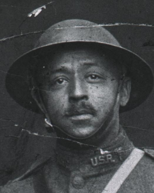 Black and white photo of African American officer in WW1 uniform standing in full view of viewer.