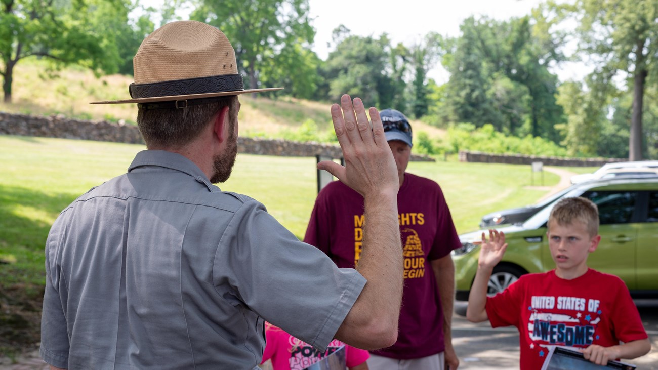 A Park Ranger swearing in a 10 year old boy to be a Junior Ranger.