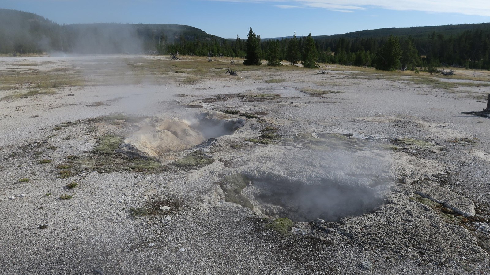 Steam rises out of two cavernous vents in a thermal basin.