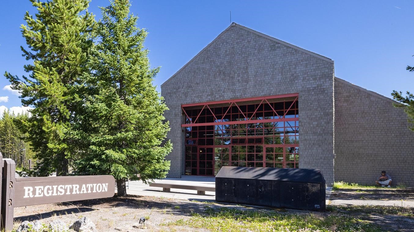 A modern stone building with large glass windows and doors, with metal accents.