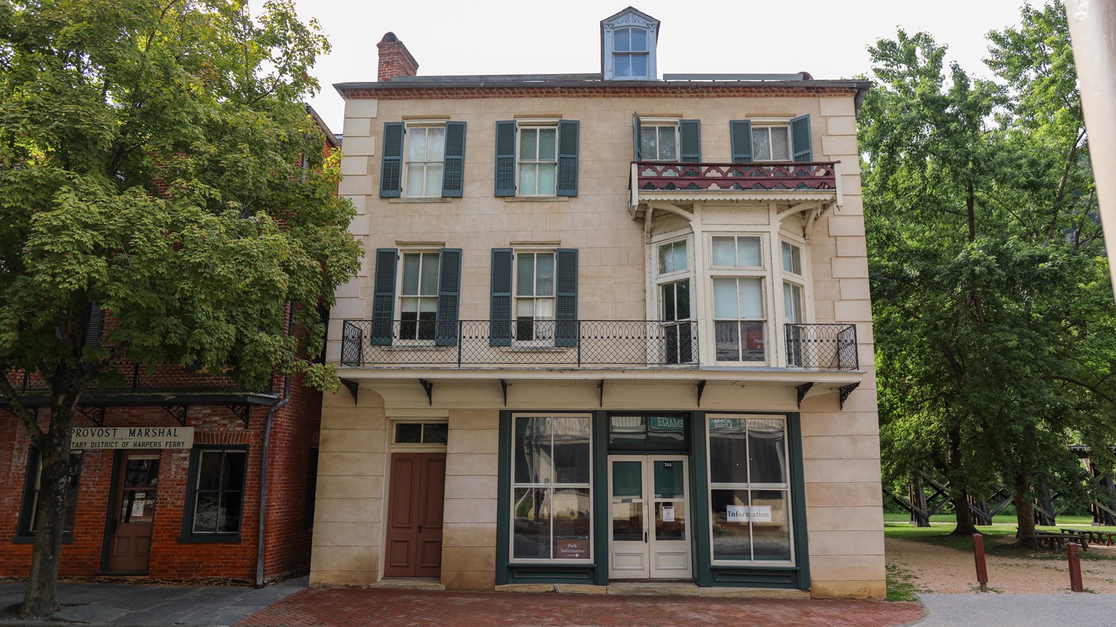 A three story white stone building with windows on each level and double doors on the bottom floor.