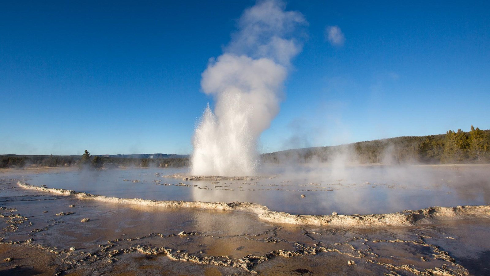 A fountain type geyser erupts in a thermal basin.