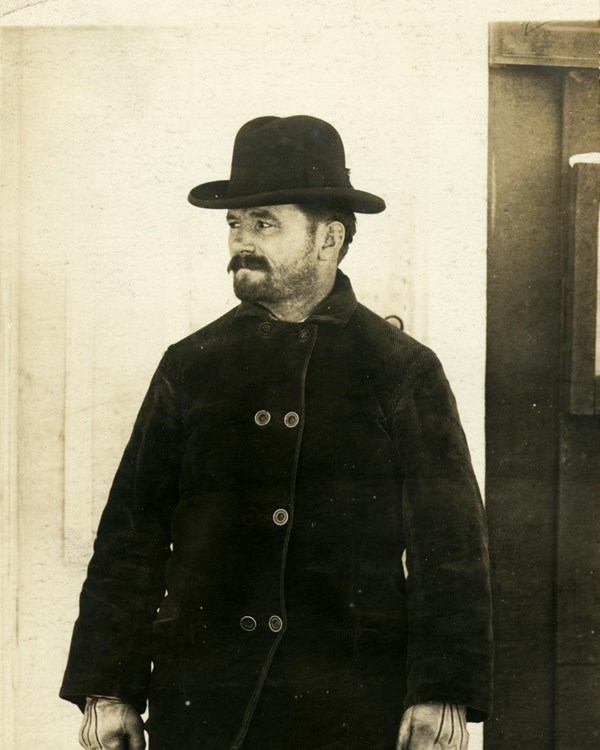 A 1904 photograph shows a rugged man outdoors in a hat and winter coat.