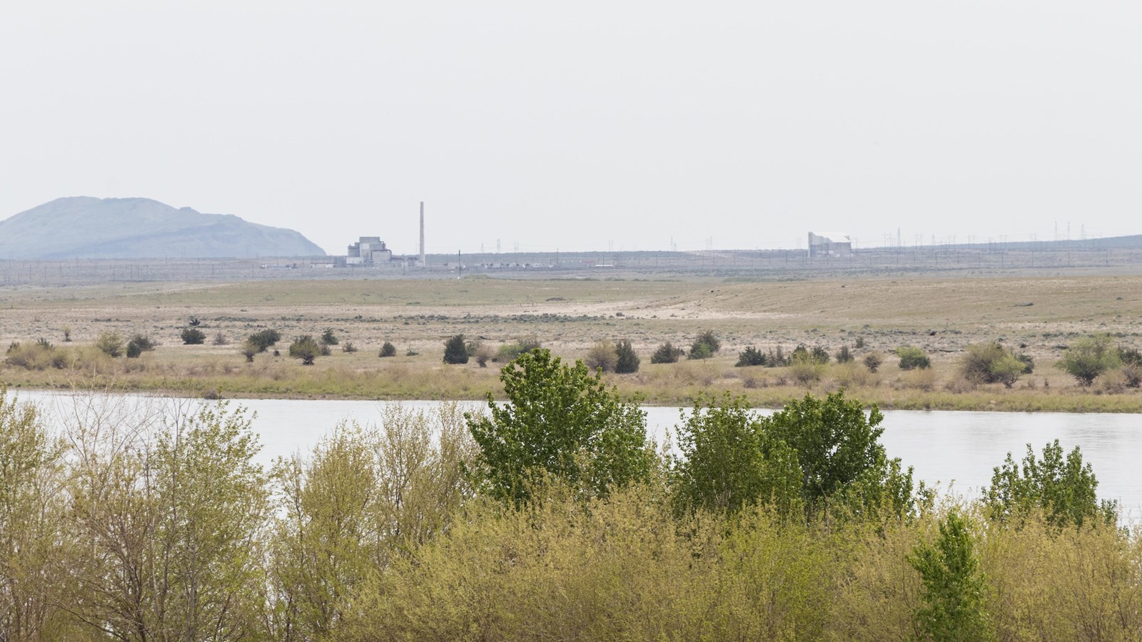 Color photograph of a waterfront area. Across the distance is a broad expanse of land w/ buildings