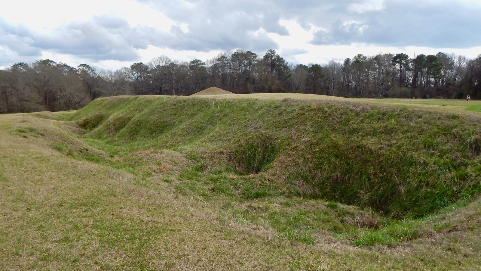 A grassy hill with various depressions lining one side.