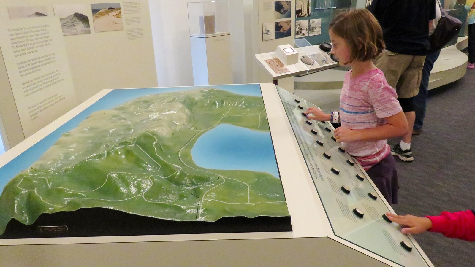 Young girl pushes buttons on the tactile map of the Sleeping Bear Dune