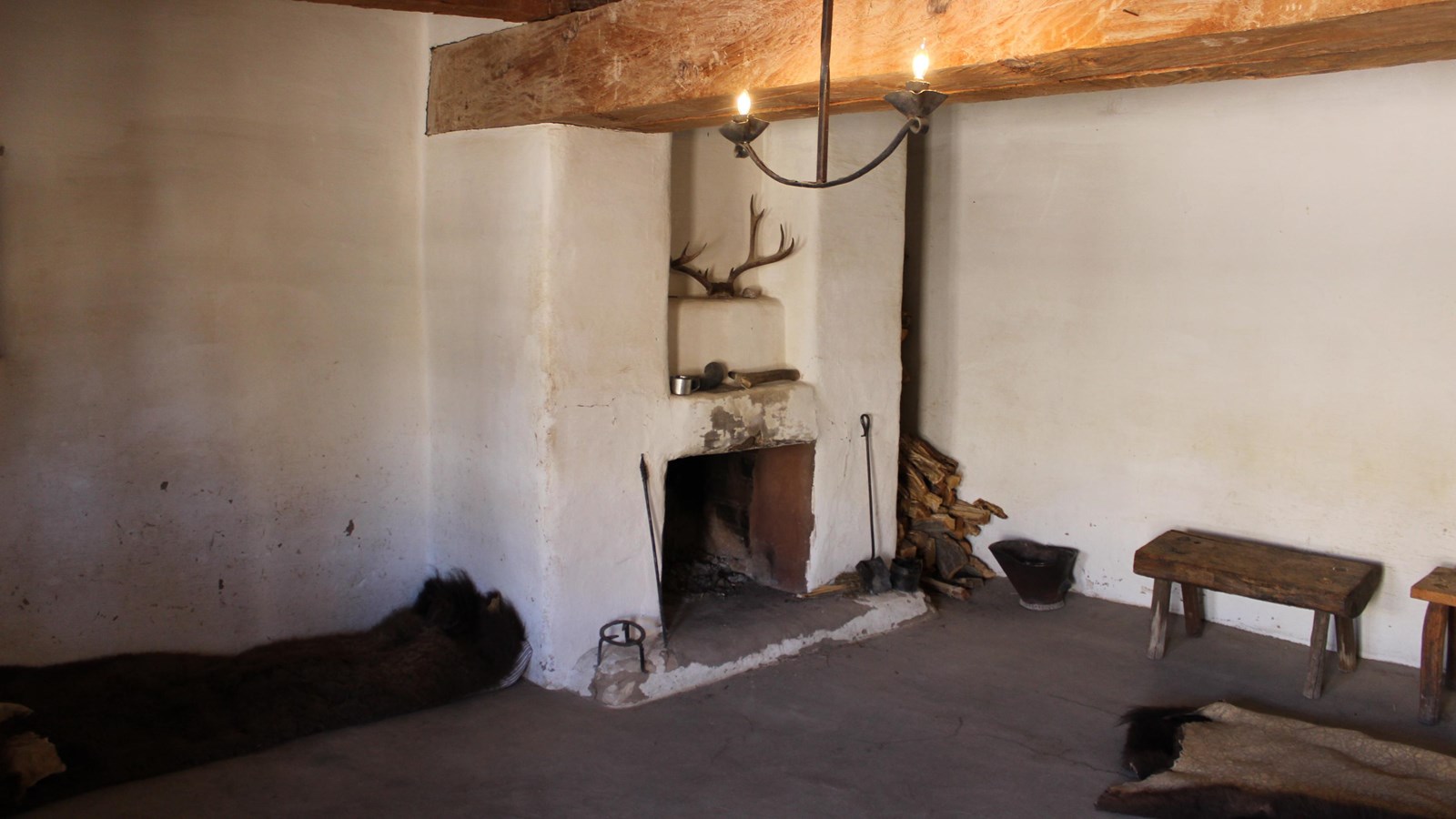 A sparsely furnished room with bison robes on the floor. 