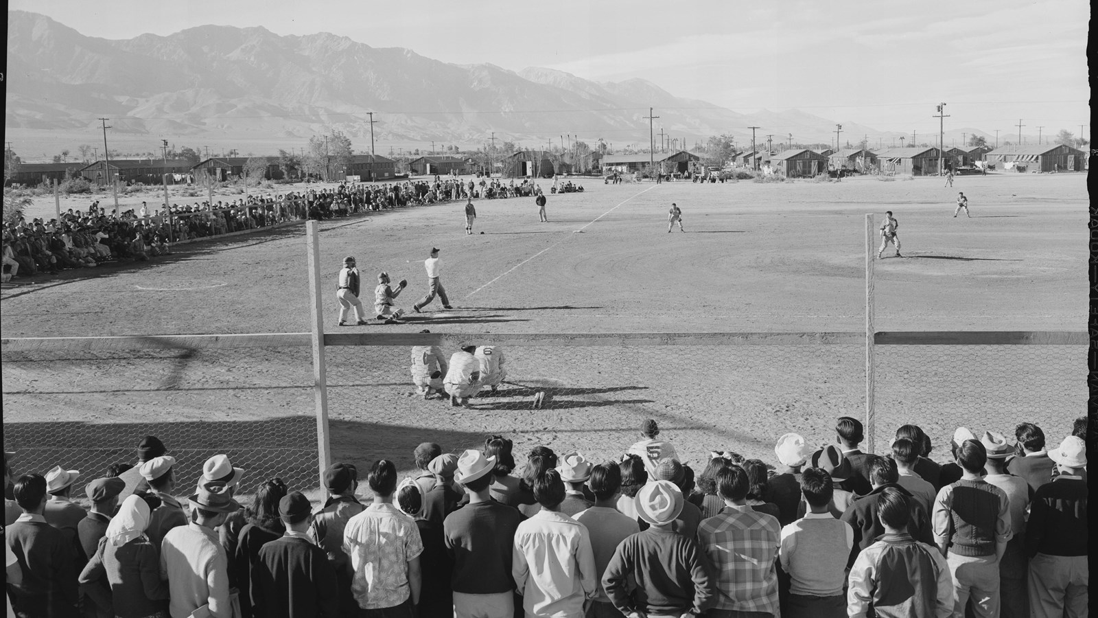 Black and white photo of Japanese Americans watching and playing baseball, 1943