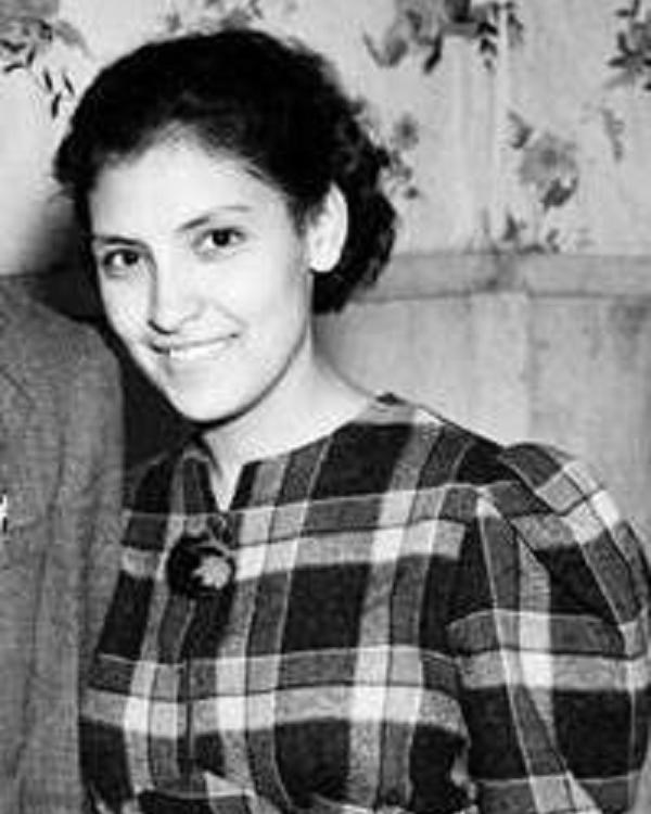 Black and white photo of a young woman in a plaid dress.