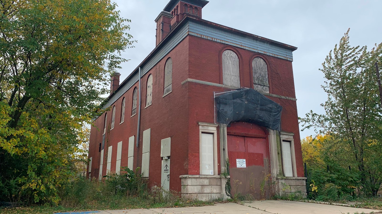 A red brick two story building with a tall watch tower towards the back of the building.