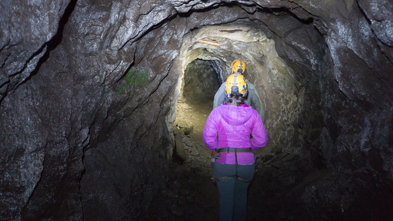 Two people walking underground in a small tunnel 