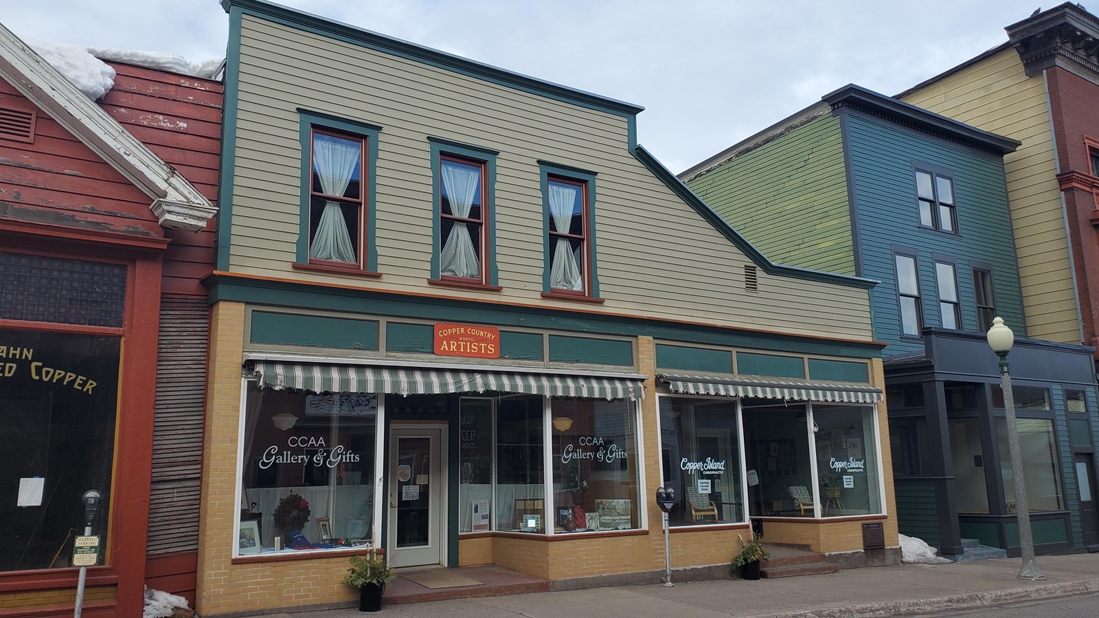 Two story building with large storefront windows. A sign reads “Copper Country Associated Artists.