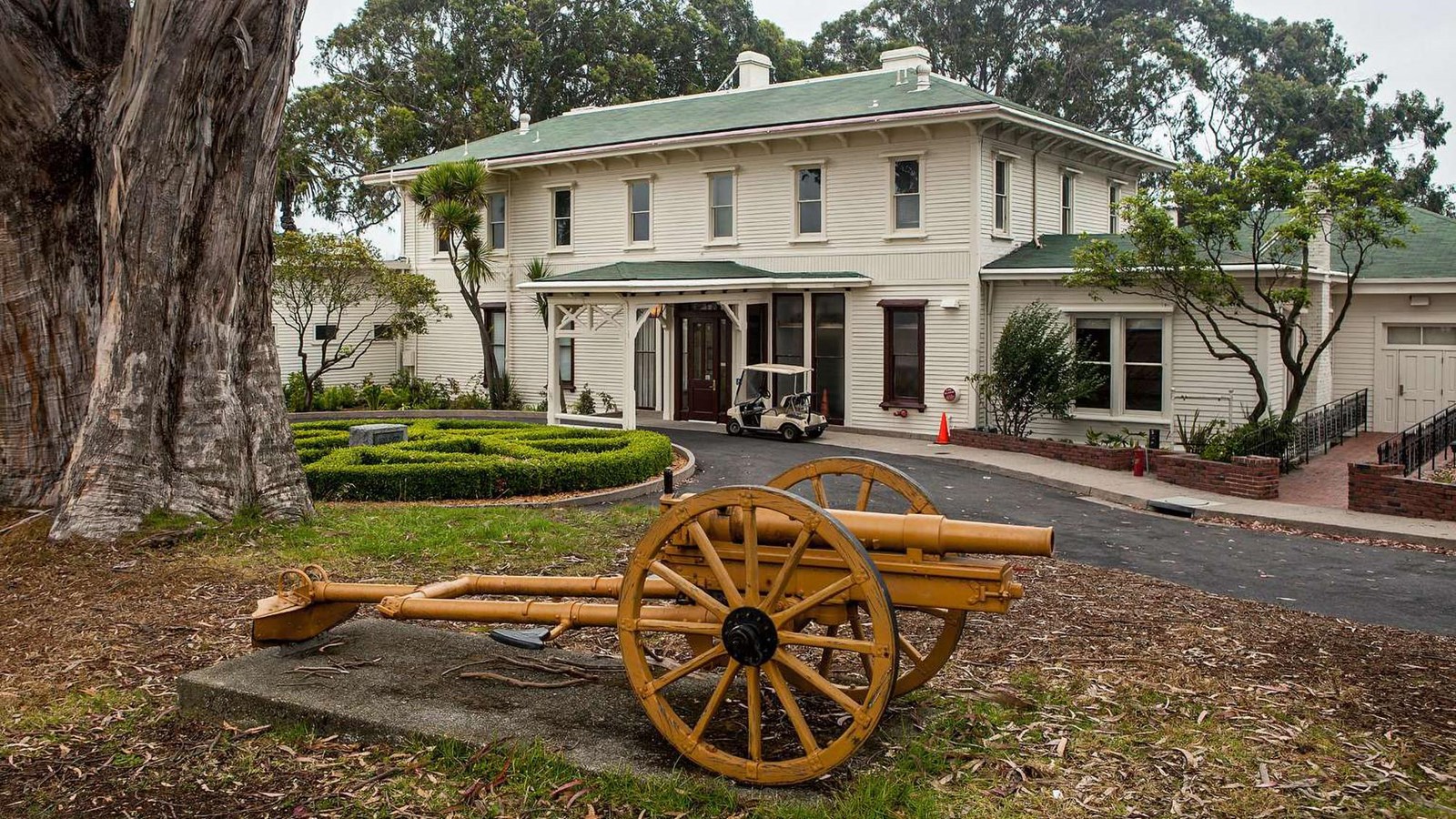  A yellow field artillery piece stands in front of the white wooden General\'s Residence.