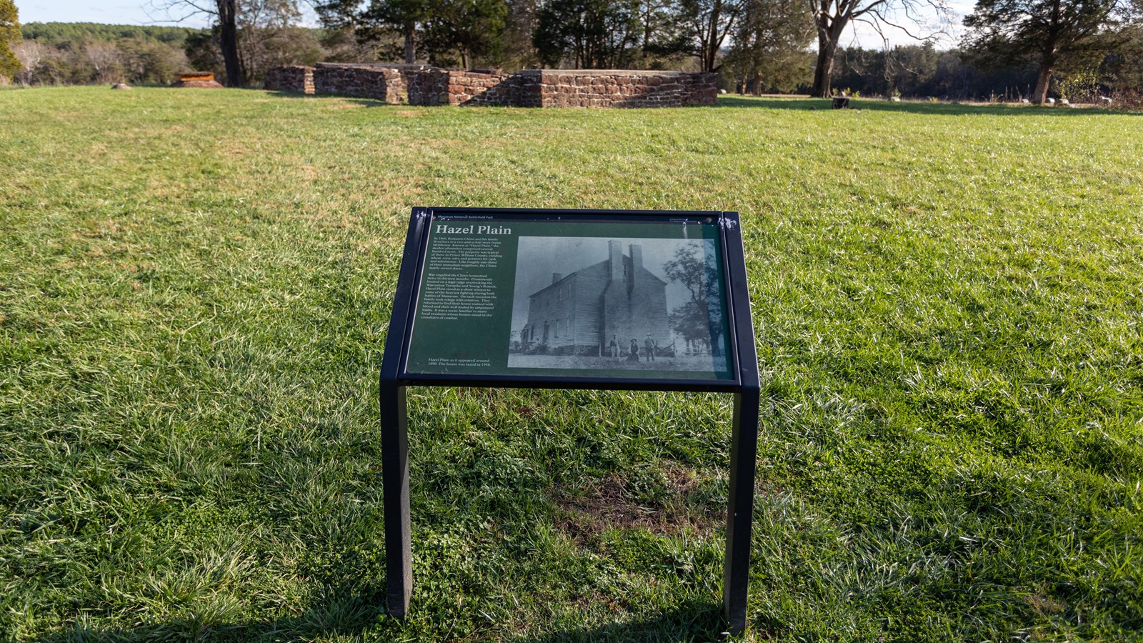 An image of Hazel Plain in 1890. A tall, large building with two chimneys is behind three men.
