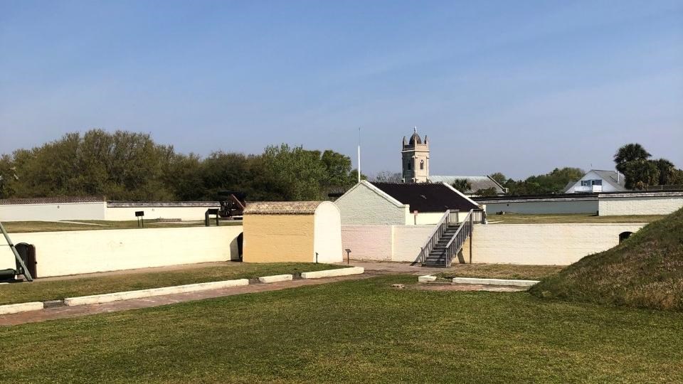 Brick structure in front of wall with doorway leading to powder magazine steep pitched roof